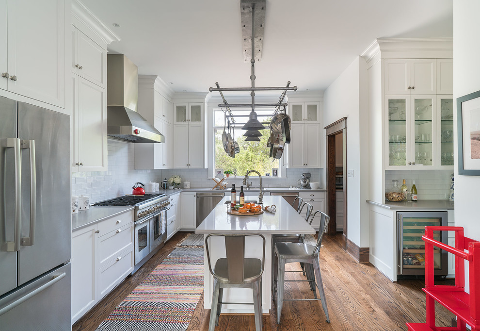 Inspiration for a mid-sized transitional l-shaped brown floor and medium tone wood floor kitchen remodel in Austin with recessed-panel cabinets, white cabinets, subway tile backsplash, stainless steel appliances, an island, a double-bowl sink, white backsplash and gray countertops