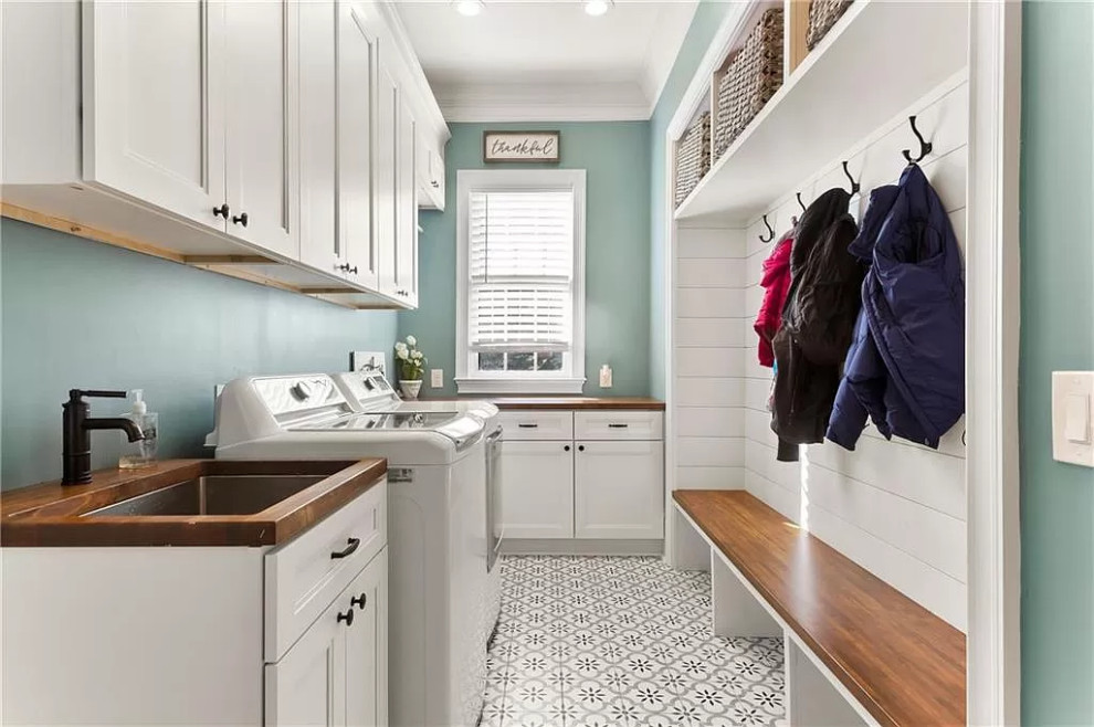 Design ideas for a mid-sized transitional l-shaped dedicated laundry room in Atlanta with an undermount sink, white cabinets, wood benchtops, green walls, porcelain floors, a side-by-side washer and dryer, brown benchtop and planked wall panelling.