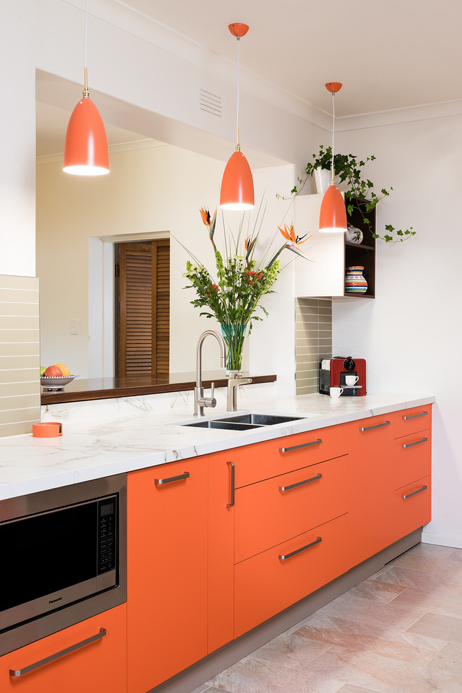 Photo of a mid-sized modern galley separate kitchen in Melbourne with a double-bowl sink, flat-panel cabinets, orange cabinets, white splashback, glass sheet splashback, stainless steel appliances, porcelain floors and beige floor.