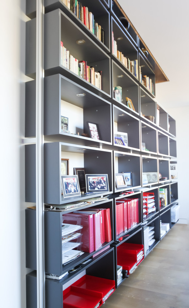 Inspiration for a large modern home office in Los Angeles with a library, white walls, light hardwood floors and a freestanding desk.