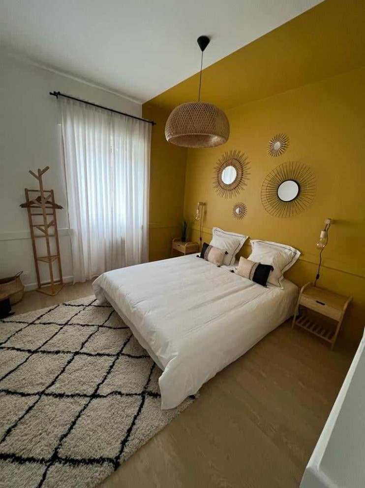 Foto de dormitorio mediterráneo con paredes amarillas, suelo laminado y suelo beige