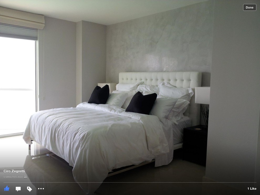 This is an example of a large contemporary master bedroom in Miami with grey walls and light hardwood floors.