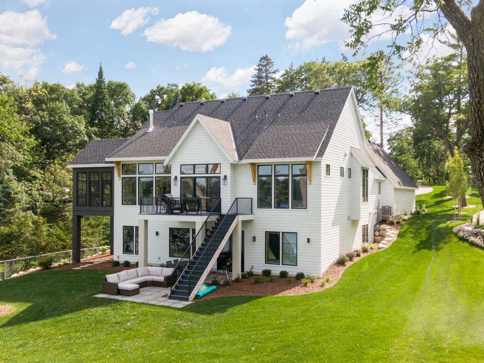 This is an example of an expansive beach style two-storey white house exterior in Minneapolis with a shingle roof and a black roof.