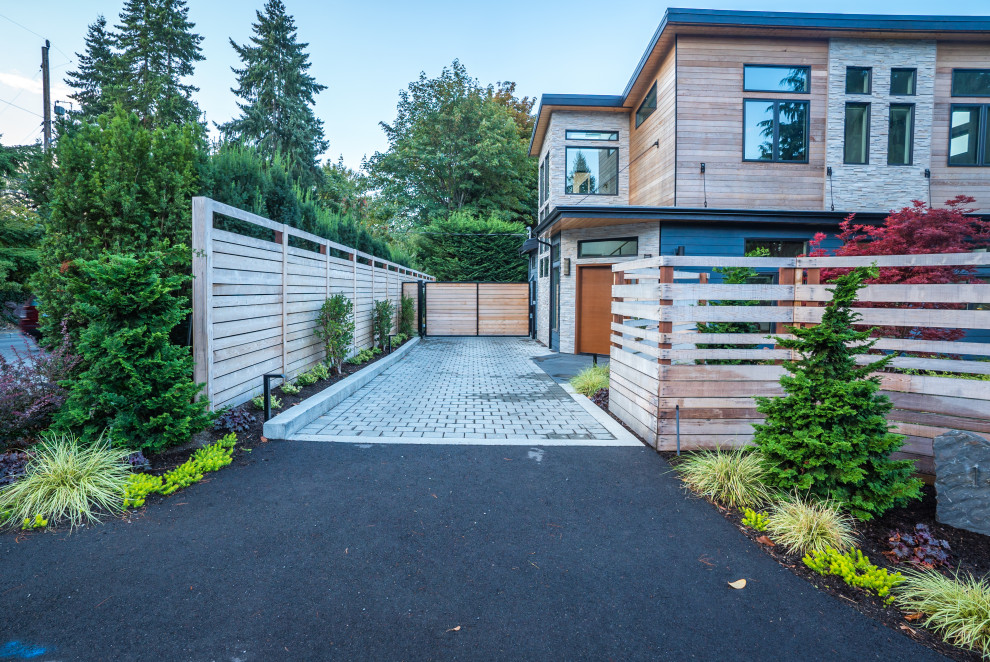 Photo of a mid-sized contemporary front yard driveway in Seattle with concrete pavers and a wood fence.