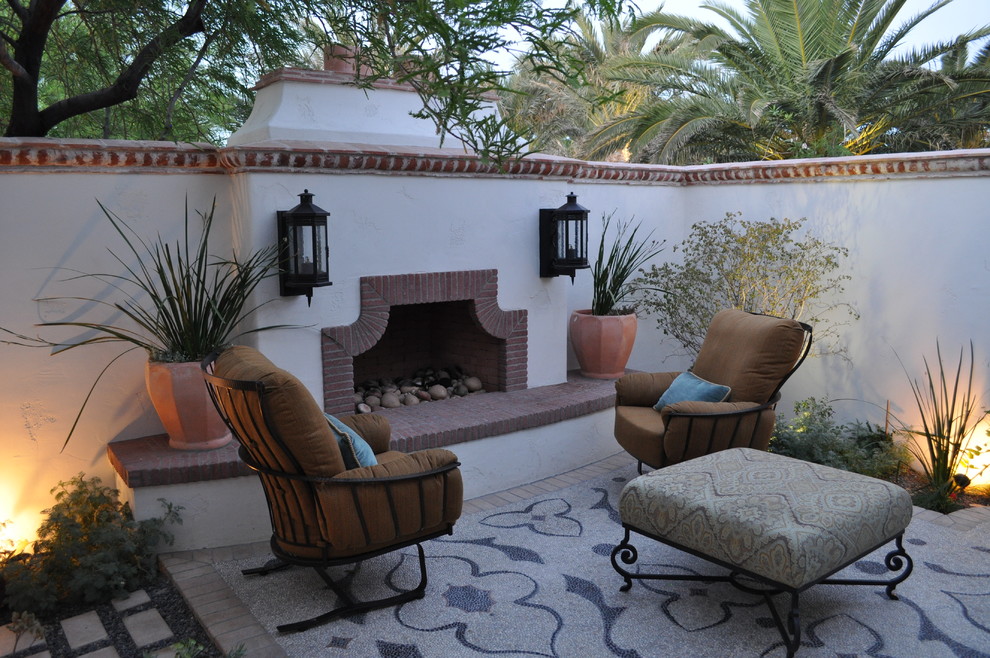 This is an example of a mid-sized mediterranean courtyard patio in Phoenix with a fire feature, tile and no cover.