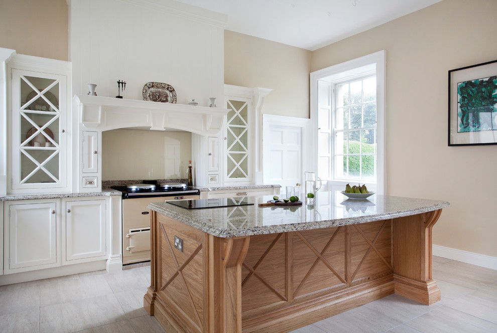 Photo of a large traditional galley kitchen in Cork with recessed-panel cabinets, white cabinets, granite benchtops, beige splashback, glass sheet splashback, with island and coloured appliances.