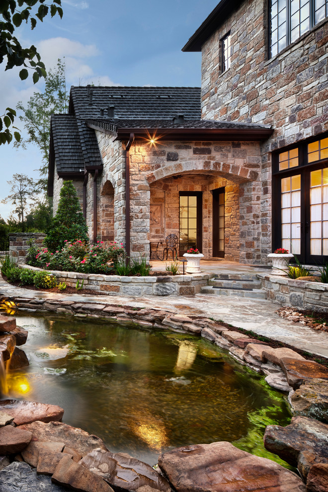 This is an example of a traditional full sun garden in Houston with a water feature and natural stone pavers.