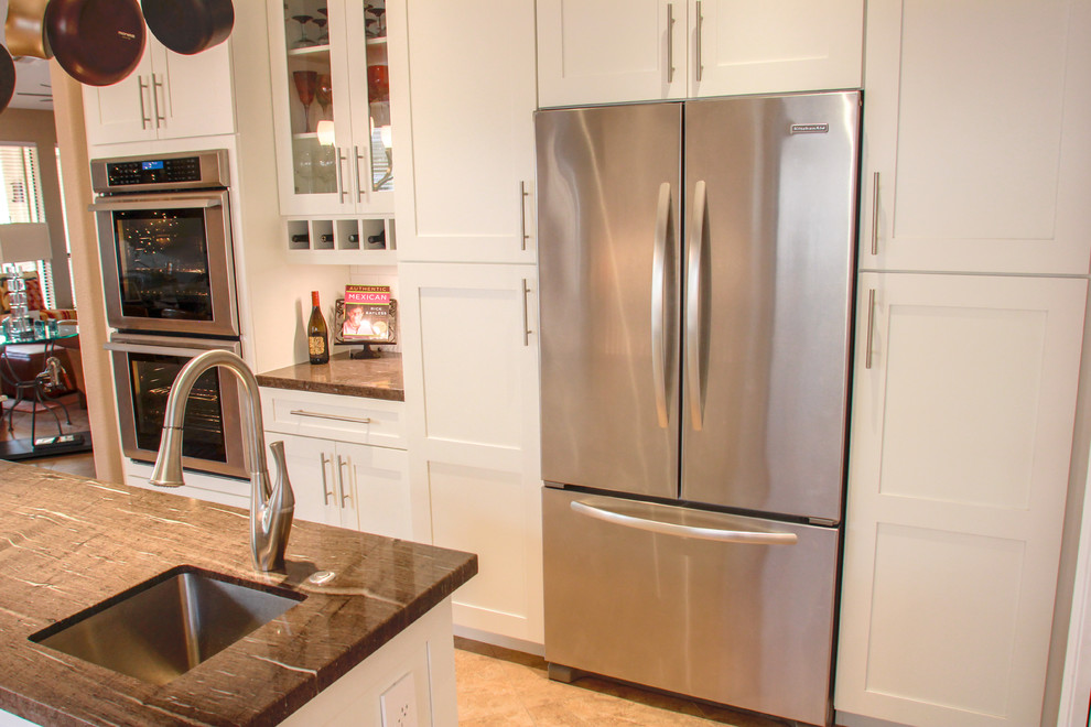 Eat-in kitchen - mid-sized transitional u-shaped porcelain tile and brown floor eat-in kitchen idea in Phoenix with an undermount sink, shaker cabinets, white cabinets, white backsplash, subway tile backsplash, stainless steel appliances, an island, granite countertops and brown countertops