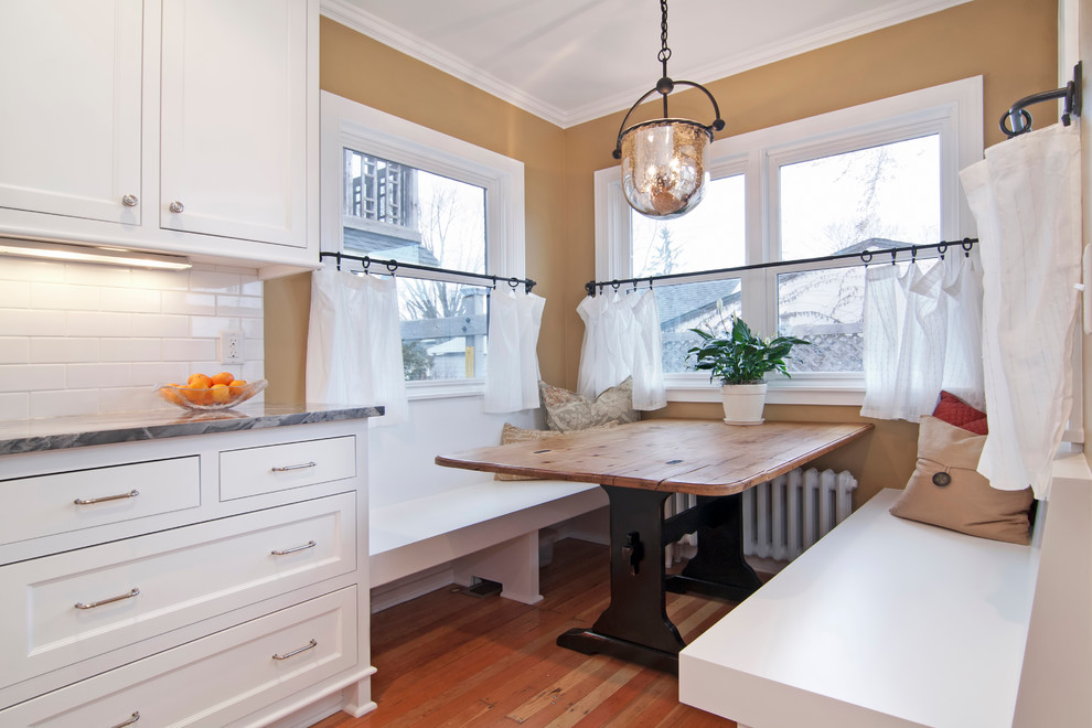This is an example of a traditional eat-in kitchen in Minneapolis with subway tile splashback and white cabinets.