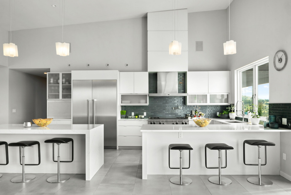 This is an example of a contemporary u-shaped kitchen in Other with an undermount sink, flat-panel cabinets, white cabinets, quartzite benchtops, blue splashback, subway tile splashback, stainless steel appliances, porcelain floors, multiple islands, grey floor, white benchtop and vaulted.