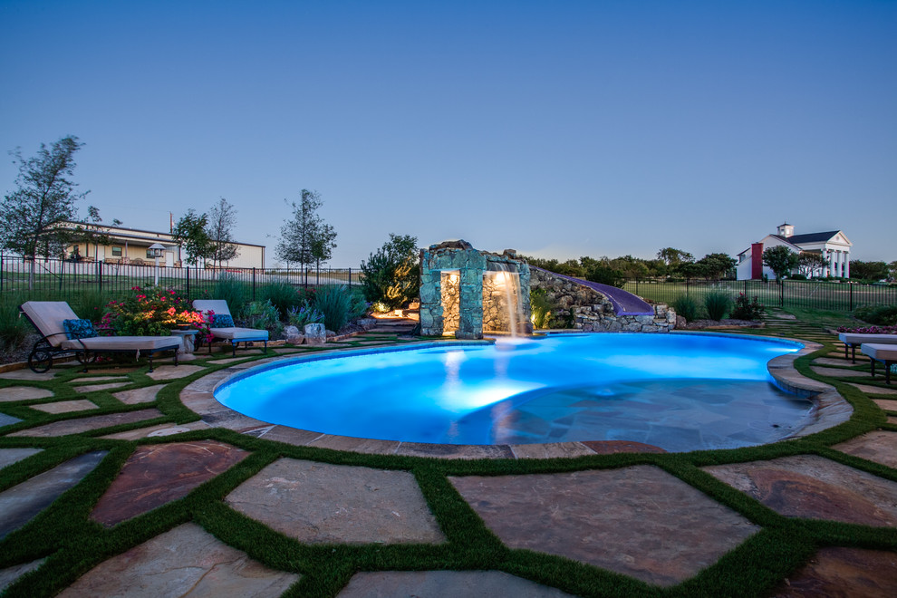 Photo of a country backyard custom-shaped pool in Dallas with a water feature and natural stone pavers.