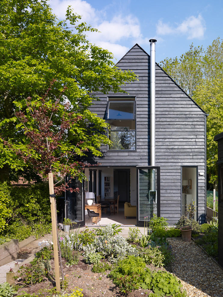 Inspiration for a transitional two-storey black exterior in London with wood siding.