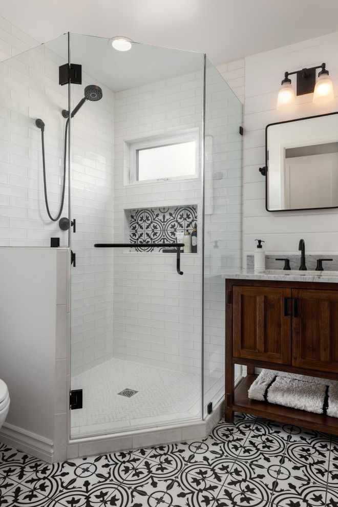 Exempel på ett litet lantligt grå grått badrum med dusch, med luckor med infälld panel, skåp i mellenmörkt trä, en hörndusch, en toalettstol med separat cisternkåpa, vit kakel, porslinskakel, vita väggar, klinkergolv i porslin, ett undermonterad handfat, bänkskiva i kvarts, flerfärgat golv och dusch med gångjärnsdörr