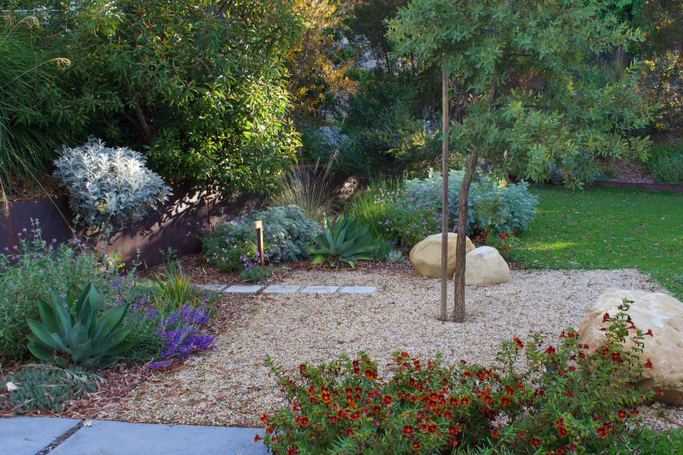 This is an example of a large modern backyard full sun xeriscape for spring in Los Angeles with with flowerbed, concrete pavers and a metal fence.