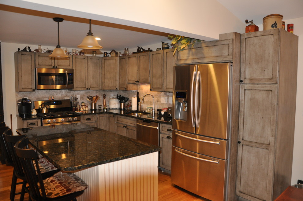 Example of a mountain style l-shaped light wood floor eat-in kitchen design in Bridgeport with an undermount sink, recessed-panel cabinets, medium tone wood cabinets, granite countertops, beige backsplash, porcelain backsplash, stainless steel appliances and an island