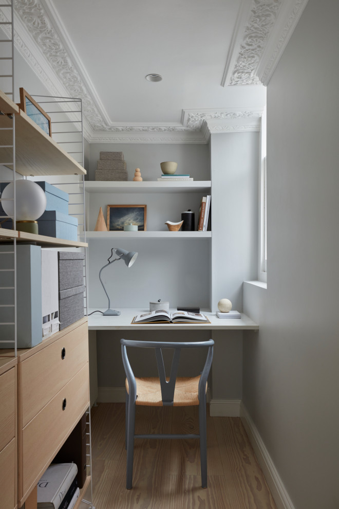 This is an example of a small contemporary study in London with grey walls, light hardwood flooring and a built-in desk.
