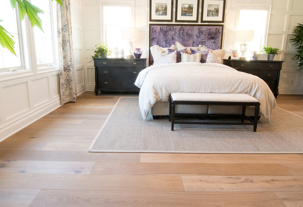 Photo of a large traditional master bedroom in Los Angeles with light hardwood floors and white walls.