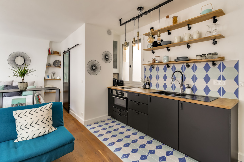 Design ideas for a small midcentury single-wall open plan kitchen in Paris with a double-bowl sink, black cabinets, wood benchtops, multi-coloured splashback, stone tile splashback, panelled appliances, ceramic floors and multi-coloured floor.