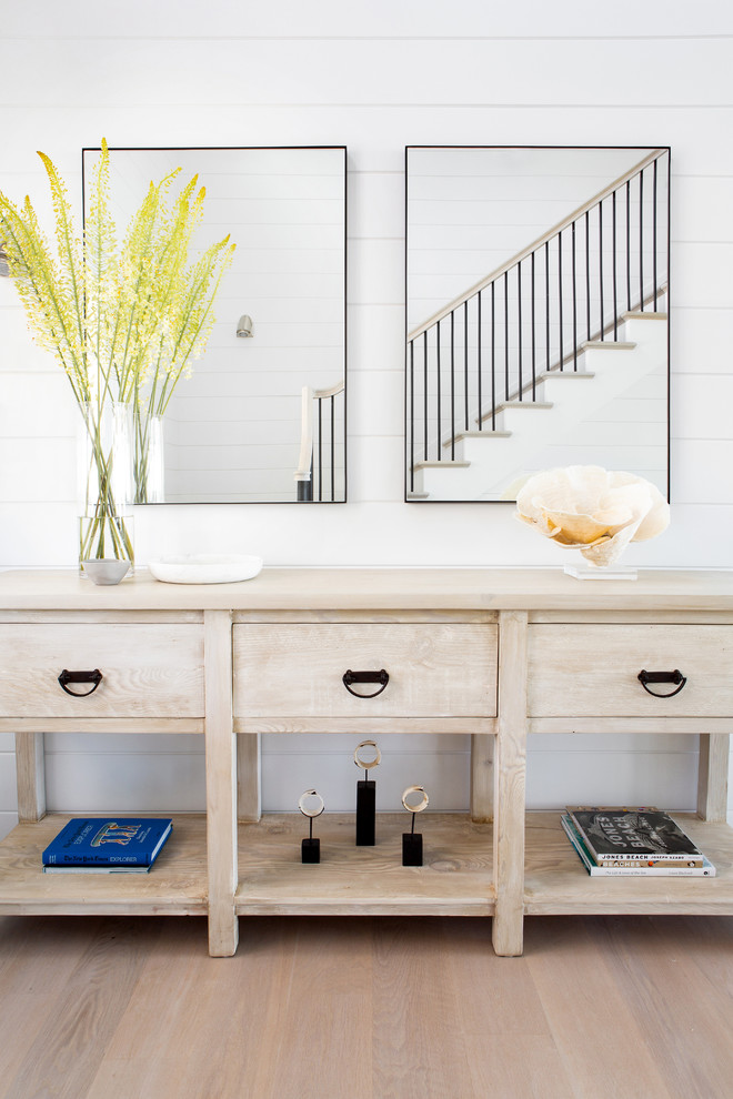 Photo of a mid-sized beach style foyer in New York with white walls, light hardwood floors, a single front door, a white front door and beige floor.