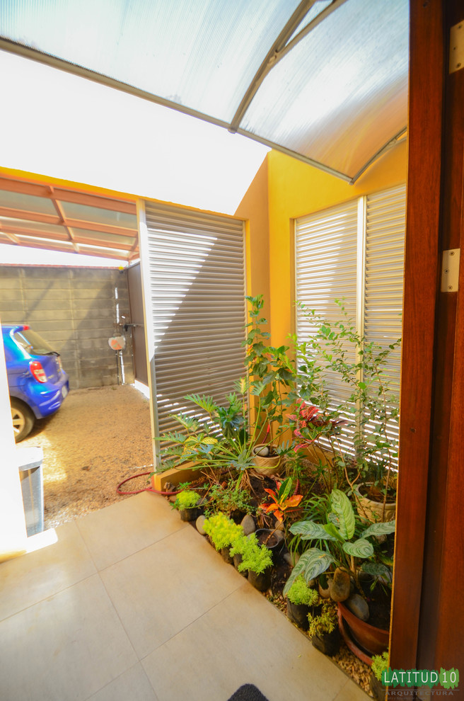 Home design - small rustic side yard gravel porcelain tile home design idea with yellow walls, a brown front door and an awning