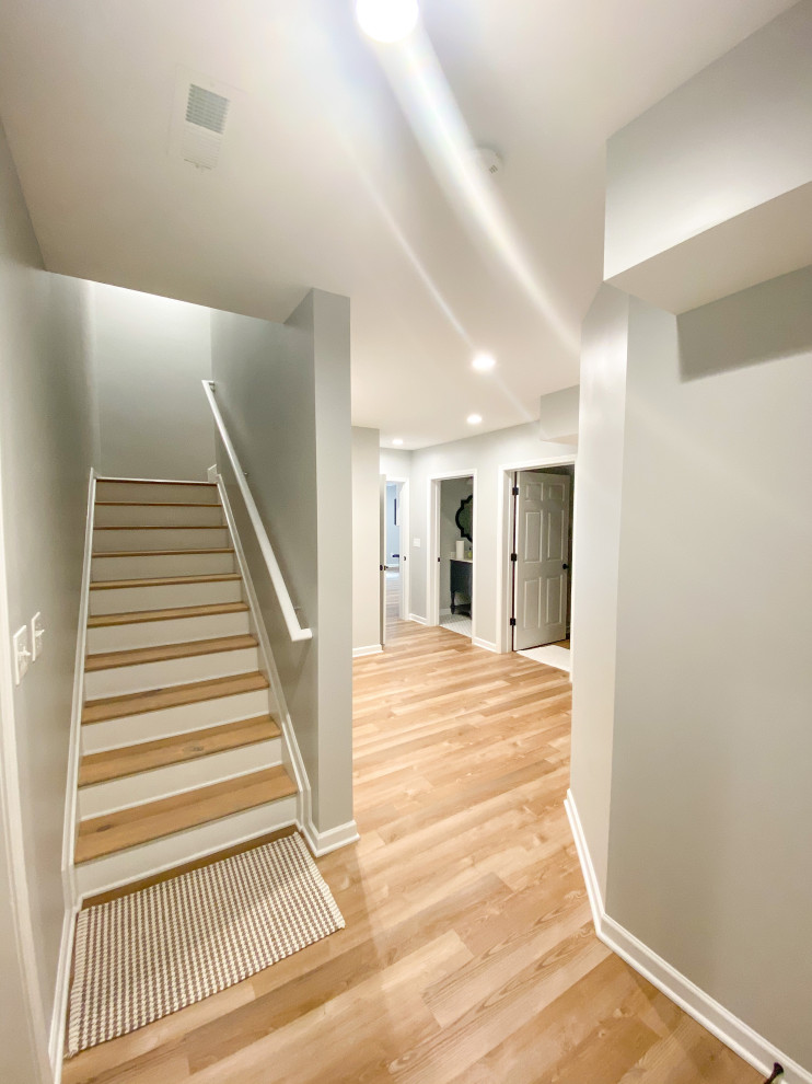 This is an example of a large walk-out basement in Atlanta with grey walls, no fireplace and brown floor.