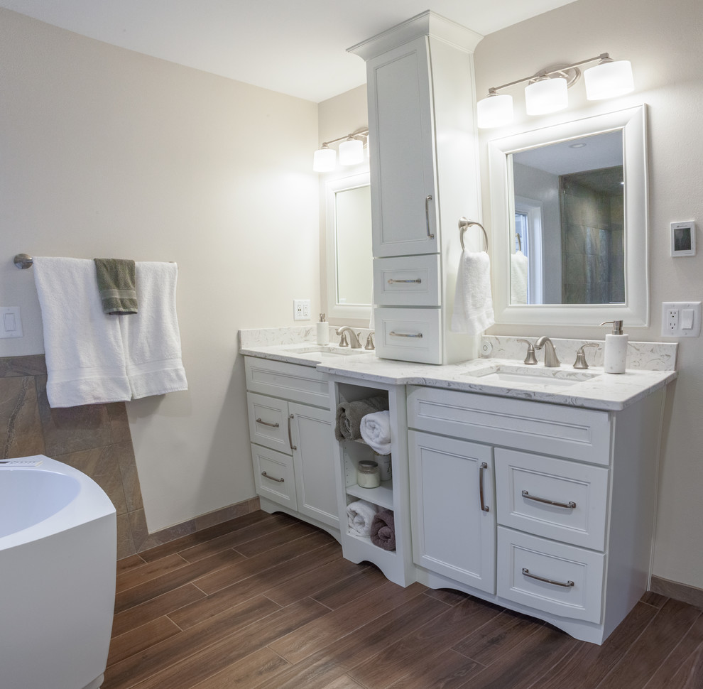 This is an example of a large transitional master bathroom in Milwaukee with a curbless shower, porcelain floors, engineered quartz benchtops, recessed-panel cabinets, white cabinets, a freestanding tub, a two-piece toilet, beige tile, brown tile, slate, beige walls, an undermount sink, brown floor and a hinged shower door.