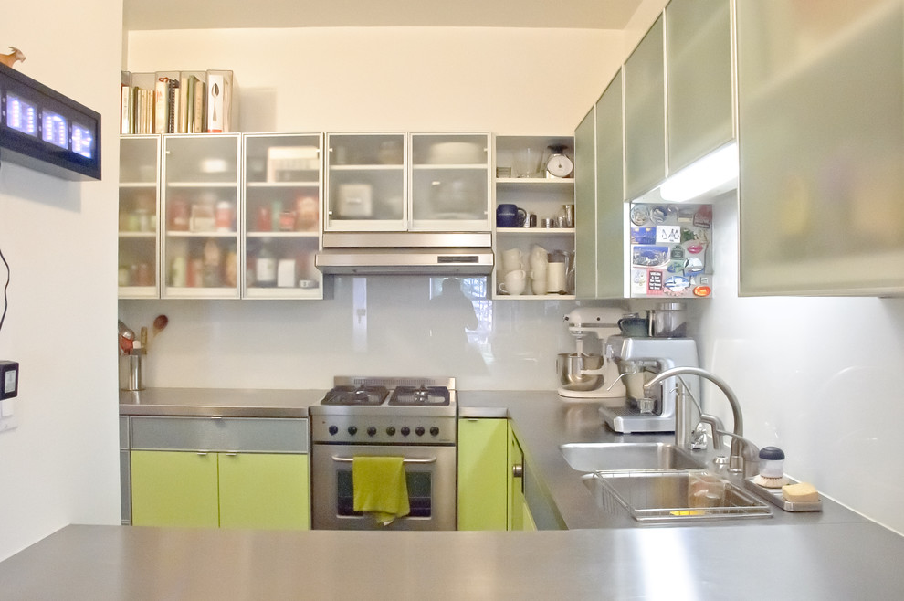 Kleine Moderne Wohnküche in U-Form mit Doppelwaschbecken, Glasfronten, grünen Schränken, Edelstahl-Arbeitsplatte, Küchenrückwand in Weiß, Küchengeräten aus Edelstahl und Kücheninsel in New York