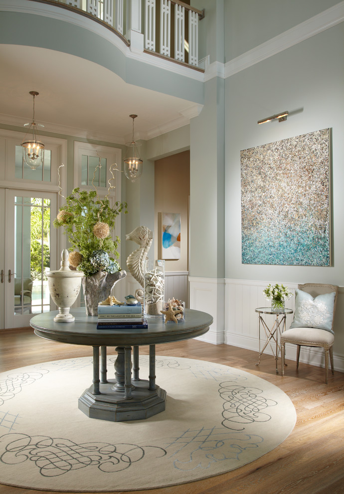 This is an example of a tropical foyer in Tampa with blue walls and a glass front door.
