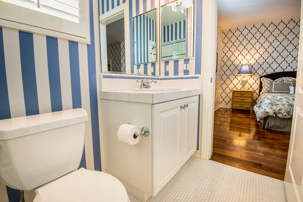 Photo of a small traditional 3/4 bathroom in Los Angeles with a drop-in sink, raised-panel cabinets, white cabinets, tile benchtops, an alcove tub, a shower/bathtub combo, a two-piece toilet, white tile, ceramic tile and porcelain floors.