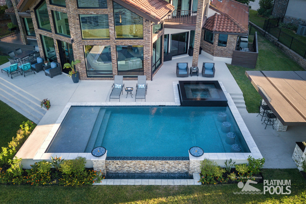 Großer Moderner Infinity-Pool hinter dem Haus in rechteckiger Form mit Betonboden in Houston