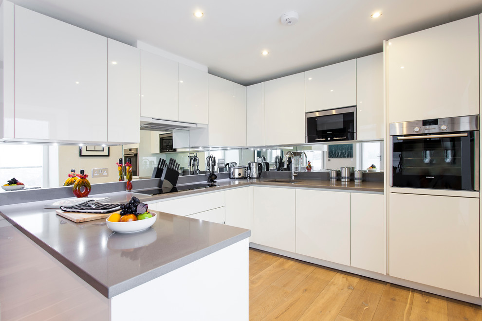 Design ideas for a contemporary kitchen in London with flat-panel cabinets and white cabinets.