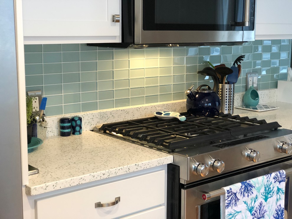 This is an example of a traditional l-shaped eat-in kitchen in Providence with a double-bowl sink, recycled glass benchtops, green splashback, glass tile splashback, stainless steel appliances and a peninsula.