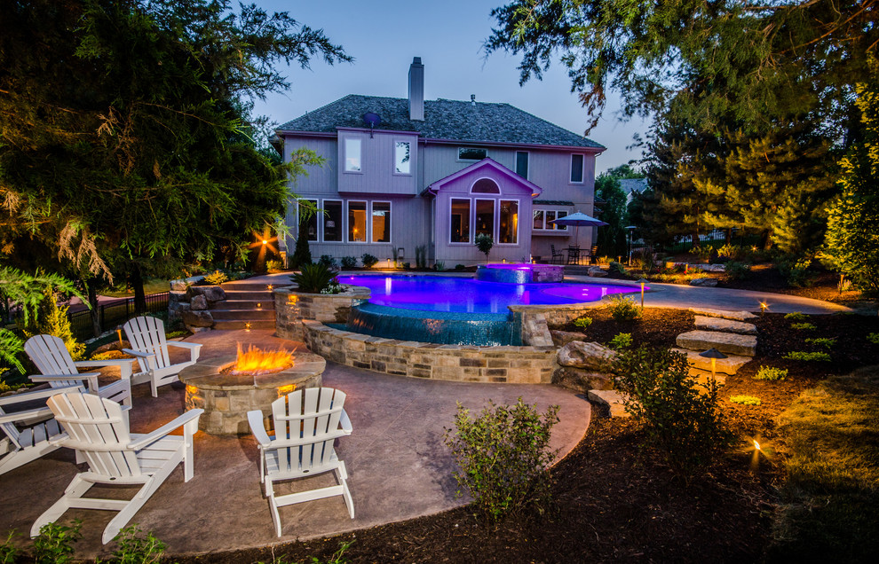 Large transitional backyard custom-shaped natural pool in Kansas City with a hot tub and stamped concrete.
