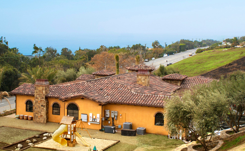 Mediterranean one-storey stucco orange house exterior in Los Angeles with a hip roof and a tile roof.