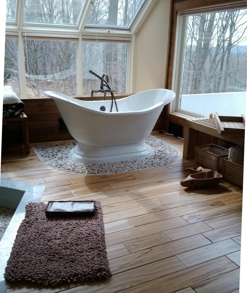 Design ideas for an expansive eclectic master bathroom in New York with a freestanding tub, an open shower, pebble tile and light hardwood floors.