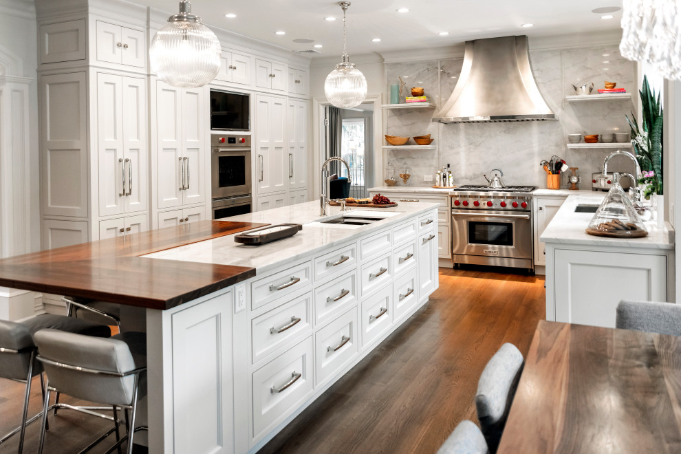 Large traditional l-shaped eat-in kitchen in New York with an undermount sink, recessed-panel cabinets, white cabinets, quartzite benchtops, white splashback, stone slab splashback, stainless steel appliances, medium hardwood floors, with island, brown floor and white benchtop.