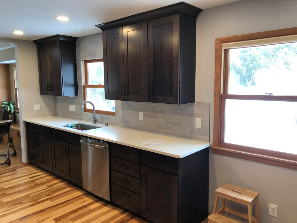 Inspiration for a mid-sized transitional galley light wood floor and brown floor eat-in kitchen remodel with an undermount sink, shaker cabinets, black cabinets, quartz countertops, gray backsplash, subway tile backsplash, stainless steel appliances, no island and white countertops