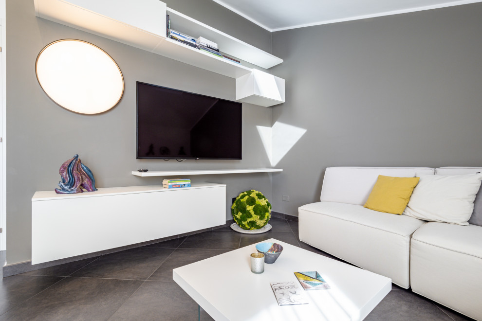 Foto di un soggiorno minimalista di medie dimensioni e stile loft con pareti grigie, pavimento in gres porcellanato, TV a parete, pavimento grigio e soffitto ribassato