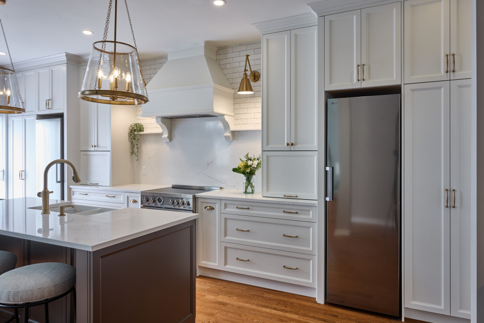 Example of a large transitional single-wall medium tone wood floor and brown floor eat-in kitchen design in Ottawa with a farmhouse sink, white cabinets, white backsplash, quartz backsplash, stainless steel appliances, an island, white countertops, quartz countertops and shaker cabinets