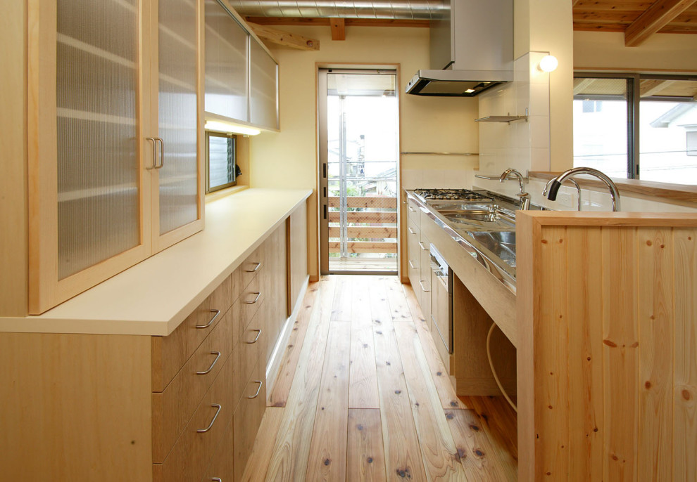Свежая идея для дизайна: кухня с двойной мойкой, светлыми деревянными фасадами, столешницей из нержавеющей стали, островом и белой столешницей - отличное фото интерьера