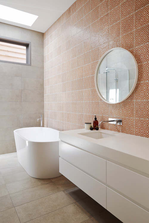 Orange textured tile in bathroom with white freestanding bath