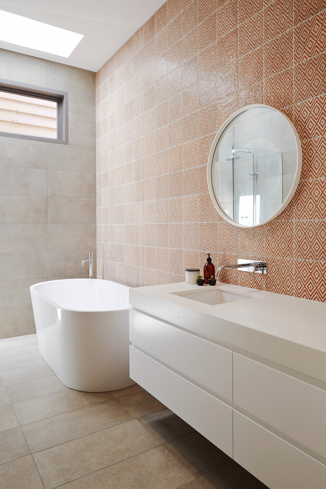 Photo of a mid-sized contemporary bathroom in Melbourne with flat-panel cabinets, white cabinets, a freestanding tub, multi-coloured walls and orange tile.