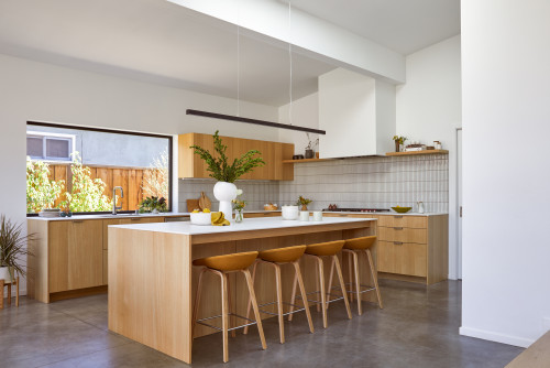 Modern light-wood slab kitchen cabinets in Montreal with a white quartz island and linear pendant lighting