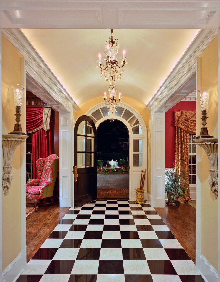 Inspiration for a large traditional foyer in Charlotte with yellow walls, marble floors, a single front door, a dark wood front door and black floor.