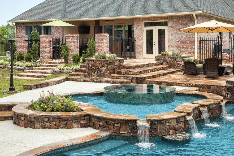 Photo of a large tropical backyard custom-shaped natural pool in New Orleans with concrete slab and a hot tub.