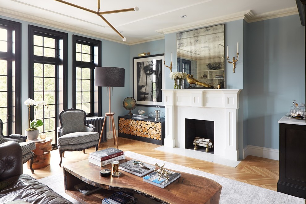 Photo of a transitional living room in New York with blue walls, medium hardwood floors, a standard fireplace and brown floor.