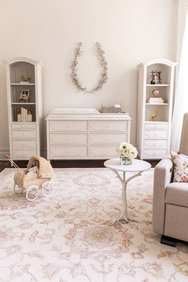 Photo of a large transitional nursery for girls in New York with white walls, dark hardwood floors and brown floor.