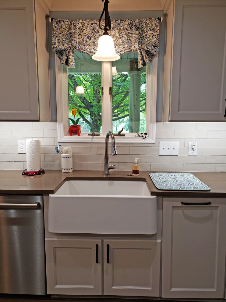 Mid-sized transitional l-shaped vinyl floor and brown floor eat-in kitchen photo in Nashville with a farmhouse sink, recessed-panel cabinets, gray cabinets, quartz countertops, gray backsplash, ceramic backsplash, stainless steel appliances, an island and brown countertops