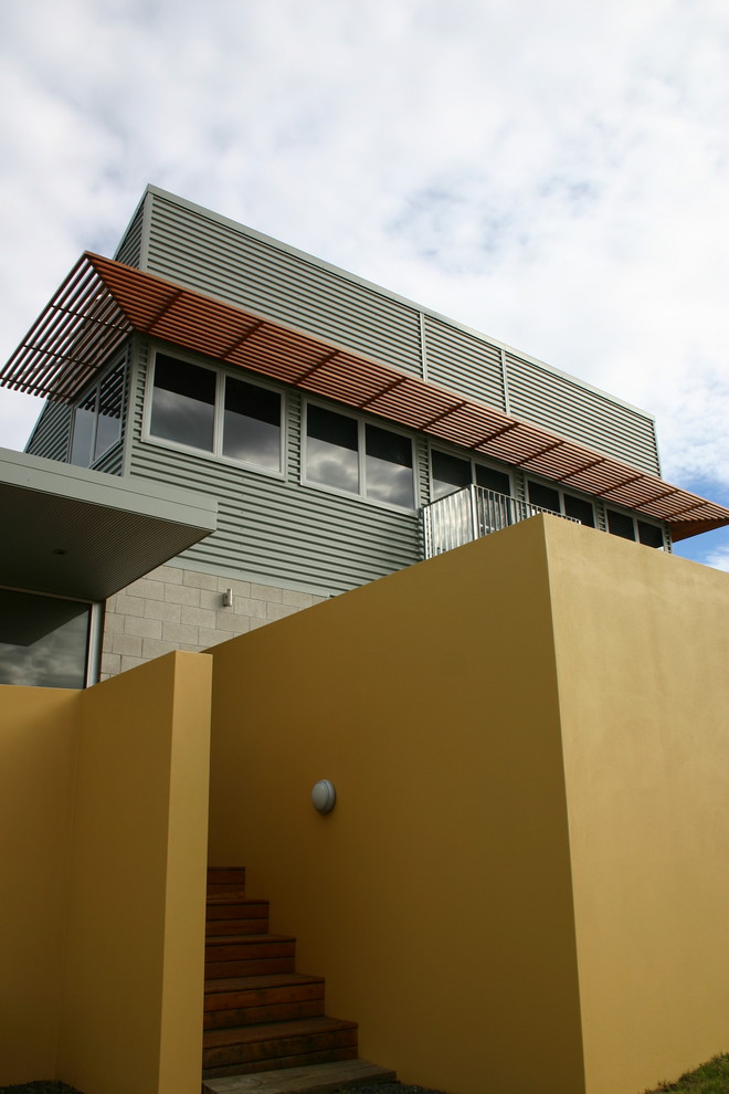 This is an example of a mid-sized industrial split-level grey house exterior in Sydney with metal siding.