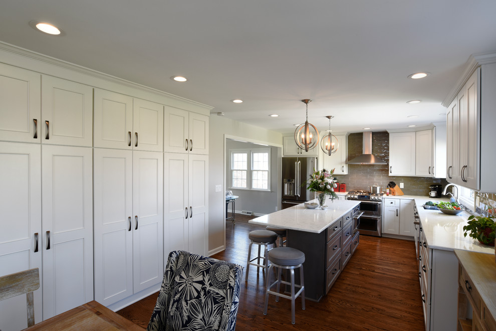 Example of a transitional l-shaped medium tone wood floor eat-in kitchen design in Orange County with a double-bowl sink, shaker cabinets, white cabinets, marble countertops, gray backsplash, glass tile backsplash, stainless steel appliances and an island